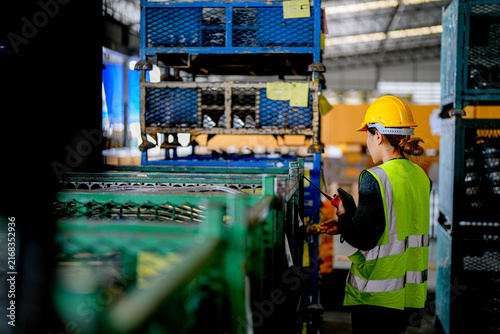 Foto Mature Asian woman working as a warehouse supervisor in protective workwear inspects automotive parts with a tablet and pen in an industrial plant that stores and assembles vehicle