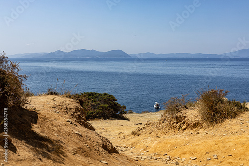 Scenic coastal landscape from Buca delle Fate near Populonia, Tuscany, Italy, with rocky cliffs, Mediterranean vegetation, green hills and blue sea. and a distant Elba island.