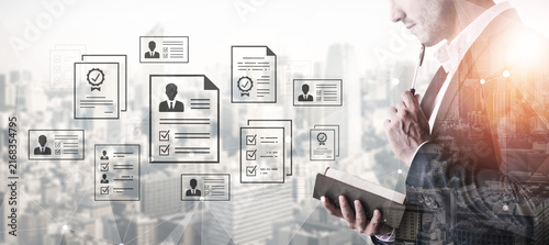 Bild auf Leinwand Business professional reviewing application documents and resumes with digital overlays of city skyline and workflow elements in a modern office environment