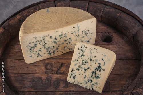 Cheese collection, piece of hard French cheese Gorgonzola with mold close up on wooden barrel