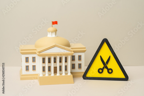 Government building and budget cut symbol. National budget sequestration. Reduction of public employees and personnel to save funds. Fiscal austerity reshapes government operations.
