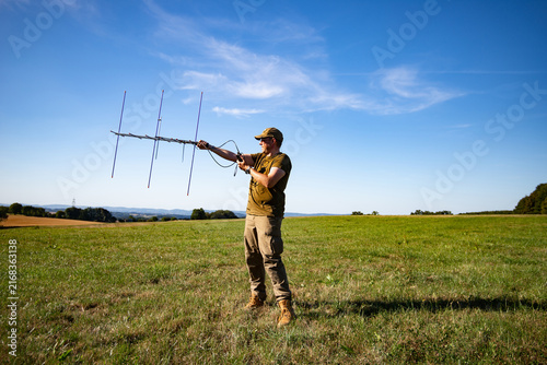 Amateur Radio Operator Using a Directional Yagi Antenna in an Open Field for Satellite Communication and Radio Direction Finding