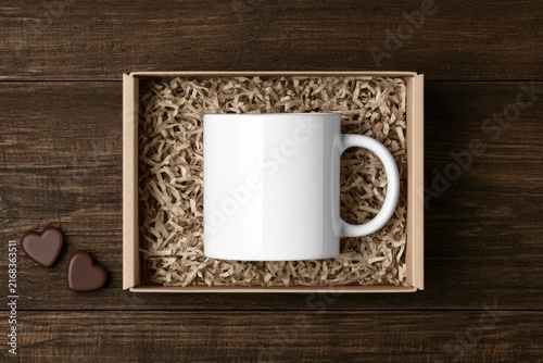 White mug nestled in shredded paper within a cardboard box, on wood