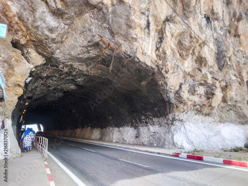 Obraz na płótnie Mountain road tunnel carved through massive rough jagged limestone cliffs showin