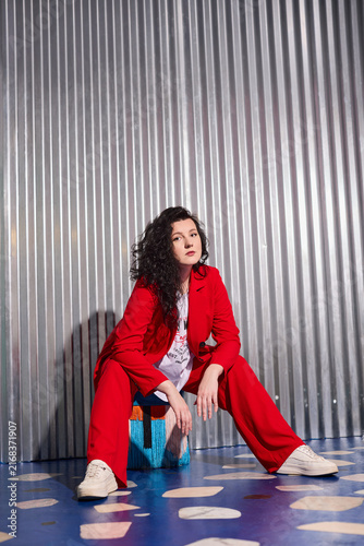 Empowered woman with curly hair poses on metallic backdrop