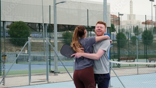 Happy man and woman high fiving and hugging after scoring a point on a pickleball court