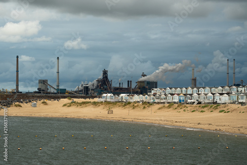 Aerial view of beach houses at the Kleine Strand with the Tata Steel industrial plant in the background under a cloudy sky IJmuiden, Noord-Holland, Netherlands.