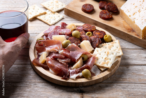 Fork picking up serrano ham from Spanish charcuterie board on wooden table