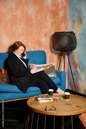 Female editor analyzing and marking magazine in cozy studio environment