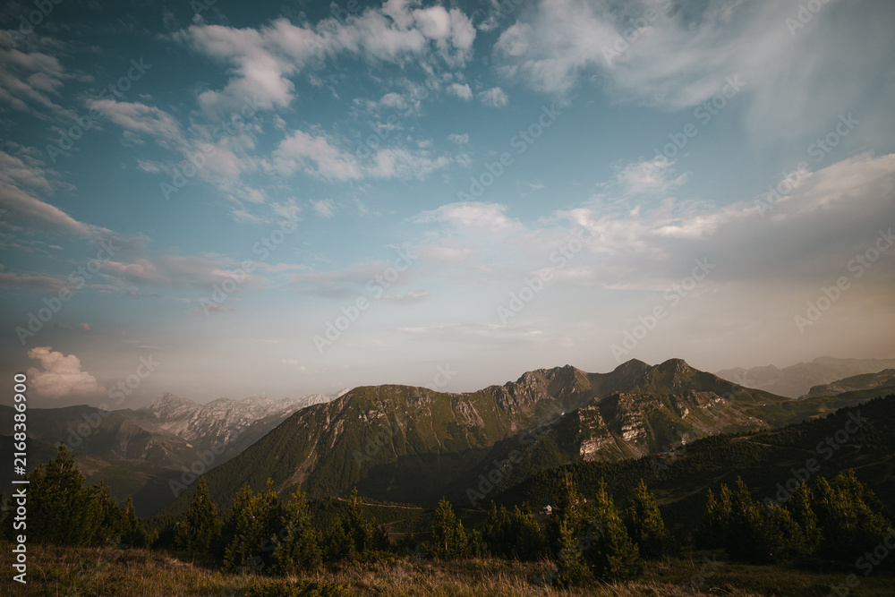 Naklejka premium Rugged mountain ridge beneath a dramatic blue sky with scattered clouds