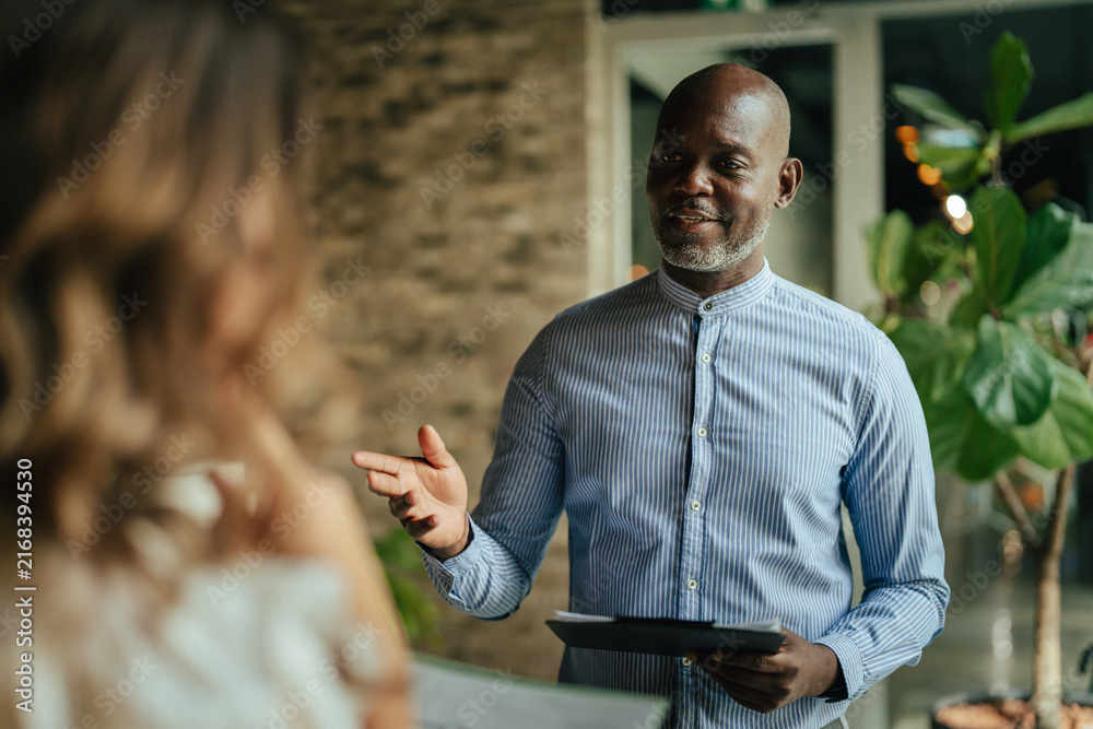 Obraz premium Black businessman discussing work with female colleague in office