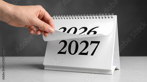 Hand Flipping Desk Calendar Page from 2026 to 2027 on Office Desk