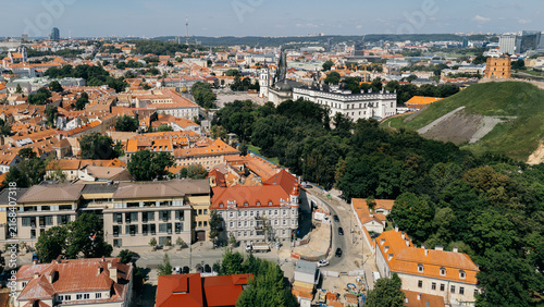 Aerial view of Vilnius old town street lined with historic buildings and a distant cathedral tower, lithuania travel content, heritage tourism marketing, city guide photography, drone stock imagery