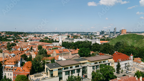 Aerial view of Vilnius skyline under a blue sky with clouds, red rooftops and green trees, lithuania travel content, city tourism marketing, drone photography stock, real estate marketing imagery