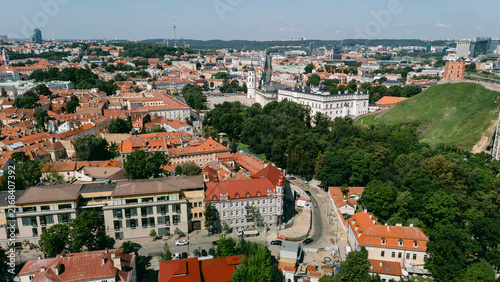 Wide aerial view of Vilnius old town with red rooftops, greenery and distant skyline, lithuania travel content, city tourism marketing, real estate drone photography, urban planning imagery
