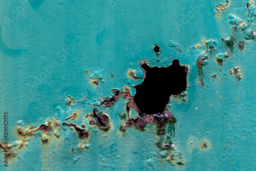 Konstfotografi Corroded metal surface with rust damage and a large hole in flaking turquoise paint
