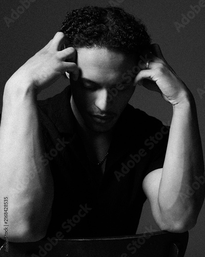Closeup portrait of a handsome afro american young man,  touches his face with his hands, keeping his eyes closed. Black and white image.