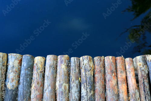 Rustic wooden logs form a border against deep blue water surface