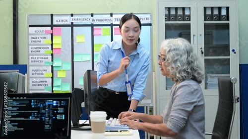 Asian software developers and engineers planning workflow on an agile scrum board with sticky notes