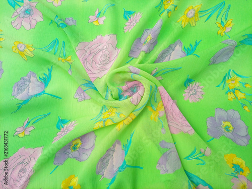 Floral pattern swirled features a variety of flowers, including roses, daffodils, and other blossoms in shades of pink, purple, and yellow, scattered across a bright green background,
