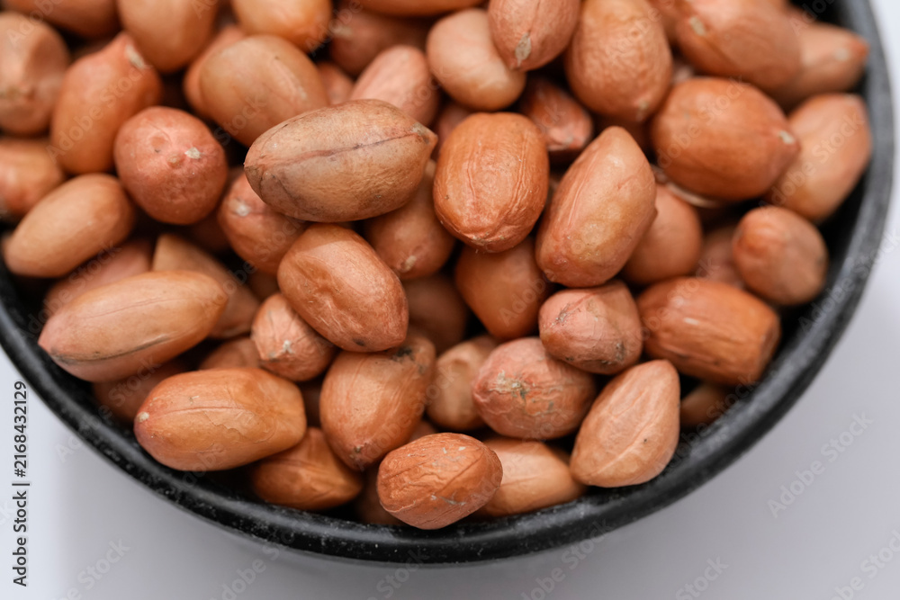 Obraz premium Raw peanut kernels in brown peel in close-up White Background