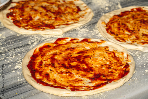 Professional chef kneading and stretching fresh pizza dough with flour in a restaurant kitchen. Authentic Italian pizzeria cooking process.