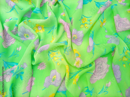 Wrinkled Floral pattern features a variety of flowers, including roses, daffodils, and other blossoms in shades of pink, purple, and yellow, scattered across a bright green background