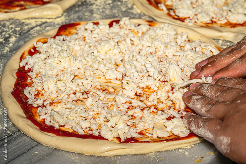 Professional chef kneading and stretching fresh pizza dough with flour in a restaurant kitchen. Authentic Italian pizzeria cooking process.