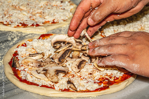Professional chef kneading and stretching fresh pizza dough with flour in a restaurant kitchen. Authentic Italian pizzeria cooking process.