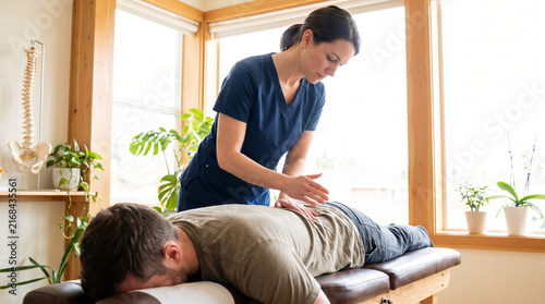 Chiropractor Adjusting Patient Back on Treatment Table in Bright Clinic