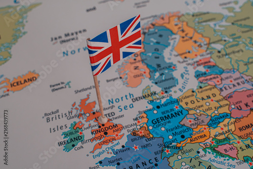 Close-up of a miniature British flag pinned on a political map of Europe over the United Kingdom.