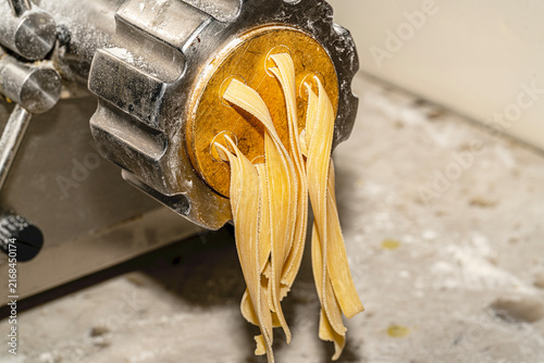 Freshly made artisanal tagliatelle pasta nests dusted with flour on a rustic wooden board. Raw homemade Italian fettuccine.