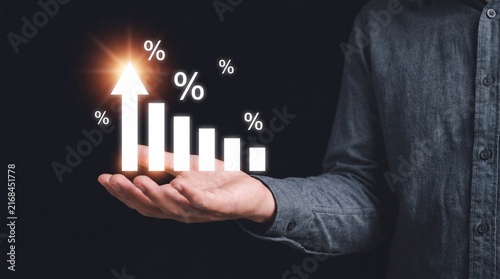 Man holding illuminated rising white percentage bars and percentage symbols on dark background