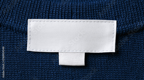 A clean mockup of a blank white clothing label tag stitched inside the neckline of a dark blue sweater or t-shirt for brand identity design.