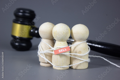 Konstfotografi Peg doll tied with rope beside the word SELL and gavel, symbolizing human traffi