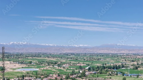 Aerial Time-lapse of Rural Landscape with Distant Qilian Snow Mountains Under Blue Sky,Wuwei city, Gansu province, China.