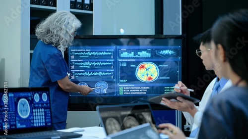 Senior doctor explains MRI brain scan results to a diverse medical team in a high tech hospital