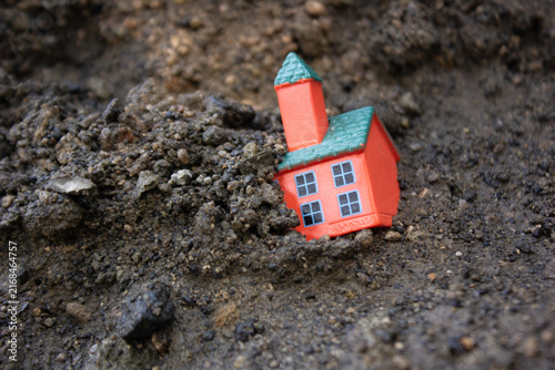 Fotografía Miniature housing buried under soil, symbolizing landslides, natural disasters,