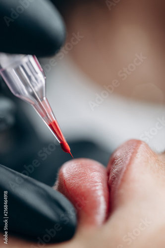 Fotografía Extreme close up of a permanent makeup artist performing a lip blush tattoo procedure with a PMU machine in a professional beauty salon