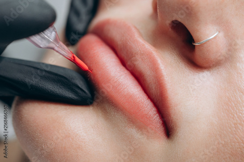 Cuadro en lienzo Macro close up of a permanent makeup artist performing a lip blush tattoo procedure with a PMU machine in a professional beauty salon