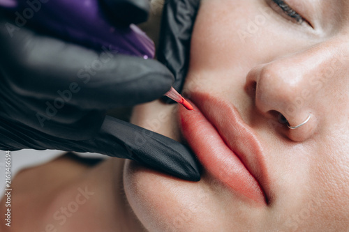Foto Macro close up of a permanent makeup artist performing a lip blush tattoo procedure with a PMU machine in a professional beauty salon