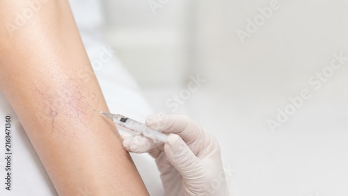 Close up of medical professional injecting substance into arm veins with syringe and gloves