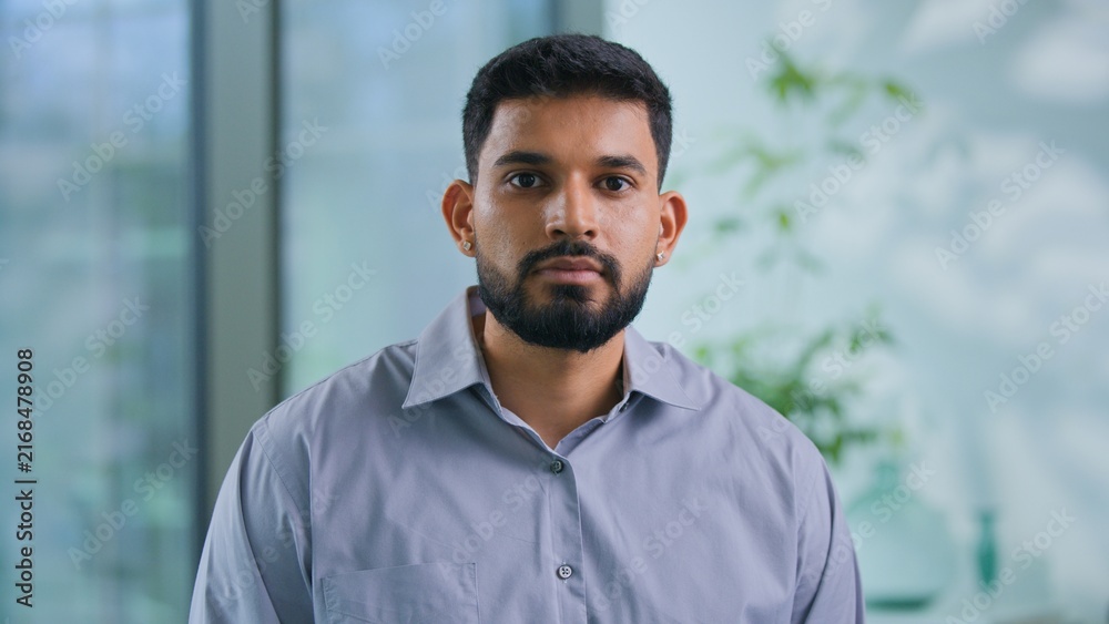 Fototapeta premium Portrait serious Arabian businessman looking at camera confident Muslim business man work posing in modern office focused Hindu male guy professional manager executive agent look working in company