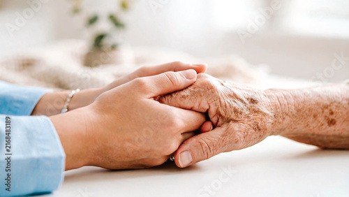Jeune femme tenant la main d'une personne âgée