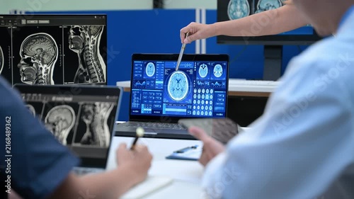 Senior doctor explains MRI brain scan results to a diverse medical team in a high tech hospital