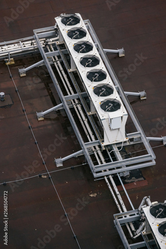 Long white HVAC unit with six circular fans mounted on grey steel frame. Top down architectural perspective. Symmetrical industrial engineering layout with geometric precision.