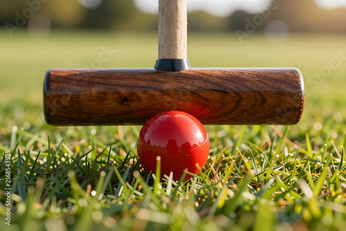 Extreme close-up of a wooden croquet mallet hitting a colorful resin ball.