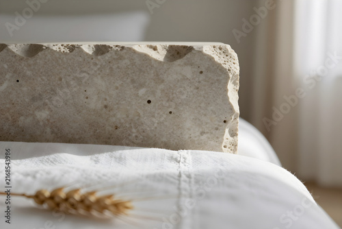 Extreme close-up of porous travertine stone texture meeting white linen bedsheets.