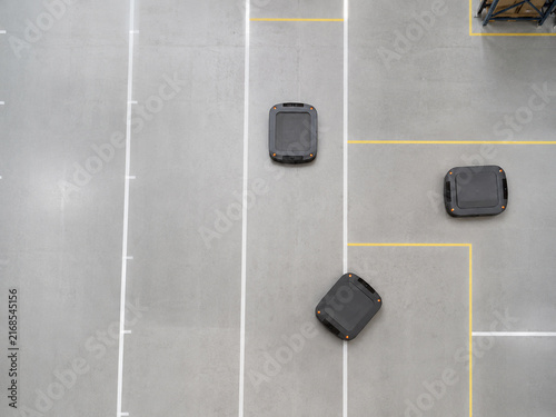 Multiple autonomous mobile robots navigating marked lanes on warehouse floor from overhead view