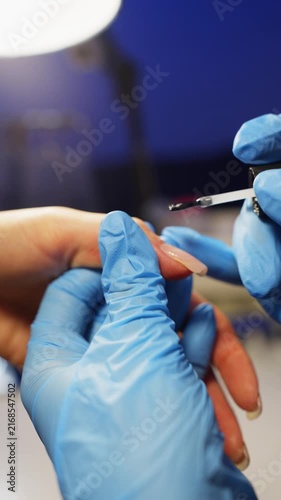 Nail technician applying decorative nail polish on woman fingernails during professional manicure in beauty salon focused on feminine beauty and personal care. High quality 4k footage